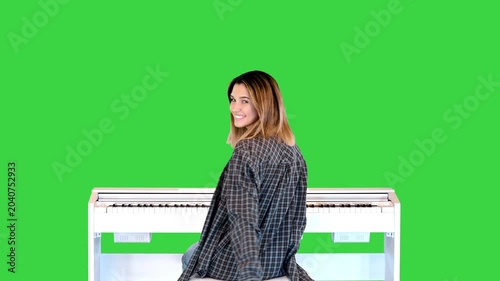 Inspired young woman is very glad of her success in studying piano on a Green Screen, Chroma Key.