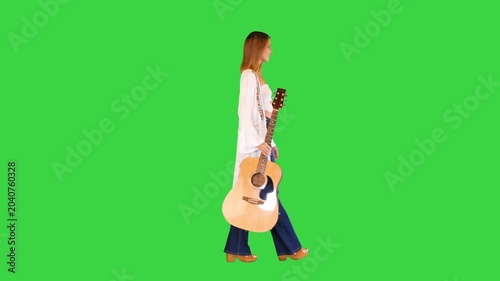 Beautiful young woman walking around with an acoustic guitar on a Green Screen, Chroma Key.