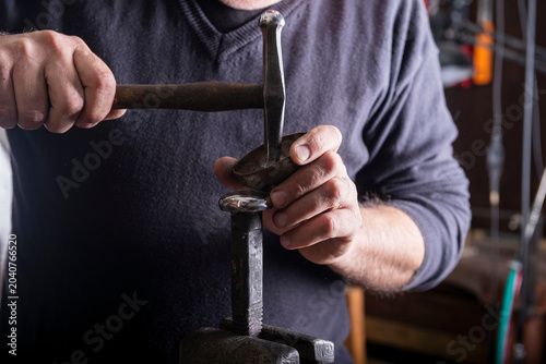 Fotografia Artisan hands working metal with hammer and tool