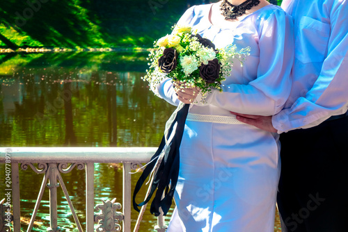 Wedding. stylish bride and groom in park are holding Bridal bouquet of flowers in brown tones with a ribbon