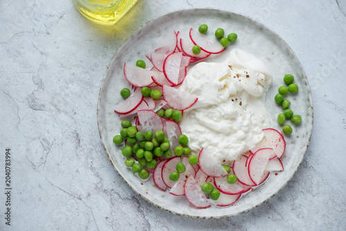 Vegetable salad with torn burrata cheese on a white stone background, horizontal shot, elevated view