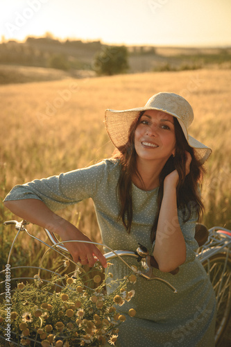 woman riding a bicycle through a golden wheat field at sunset, enjoying a warm summer evening, freedom, happiness, countryside lifestyle and travel adventure