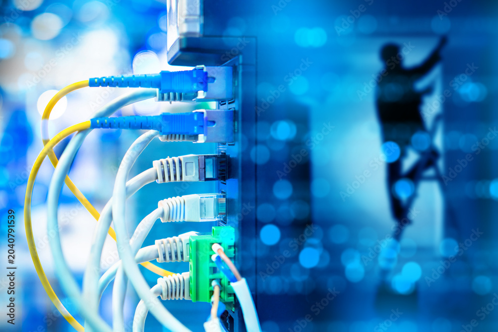 Fototapeta premium Network infrastructure, cable installation. Technician works in server room while Ethernet and fiber optic cables connect data equipment.