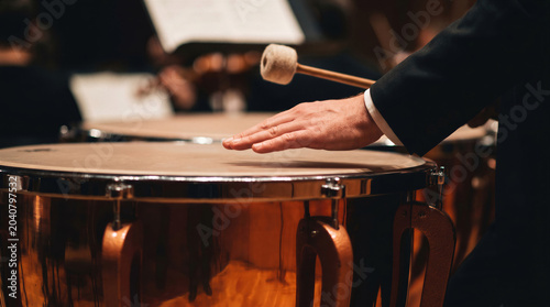  Close up of professional musician playing timpani drum in symphony orchestra with mallet. Classical music performance.