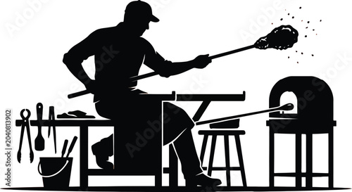 Glassblower shaping hot molten glass with blowpipe