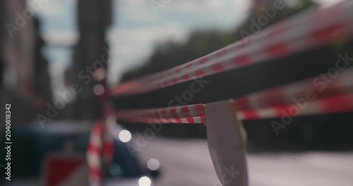 Red and white barrier tape stretched along a city street on a sunny day during Labor Day holiday.