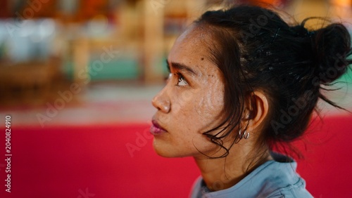Photos Young asian woman gazing upwards with focus in an indoor temple environment