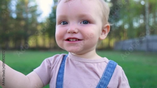 A happy toddler holds his father's hand while walking outside