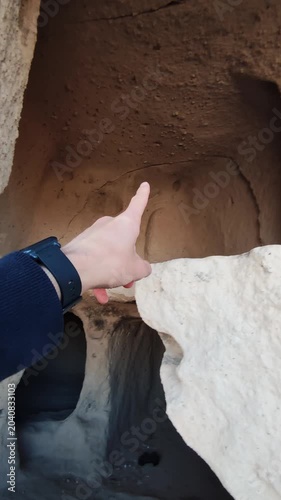Pov of male tourist exploring cappadocia caves and pointing to show them. vertical view of structures in mountains in turkey. travelling to goreme sandstone at national park. visiting famous