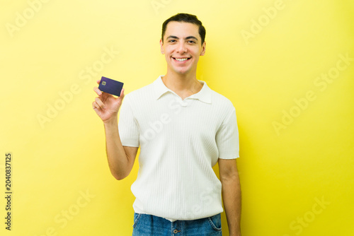 Konstfotografi Casual man smiling, holding up a credit card, doing online shopping or cashless