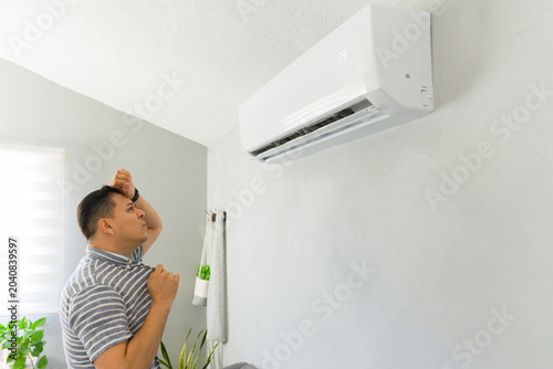 Frustrated man feeling hot during summer heatwave suffering from a broken or inefficient air conditioner