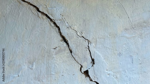 Schilderij op canvas Close-up of a cracked concrete wall with visible fractures and damaged plaster s