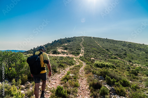 Hiker walking alone in the mountain on a hot summer day.