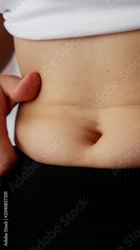 Woman pinching belly fat and Measuring waist during weight Loss transformation.