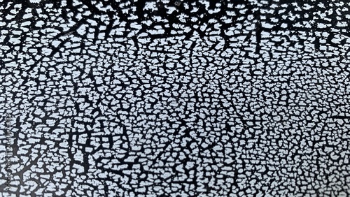 Foto Cracked surface pattern with white fragmented coating over dark background, show