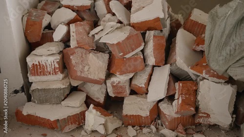 Closeup view of broken red bricks and white plaster rubble piled up during demolition or renovation work showing rough texture and debris