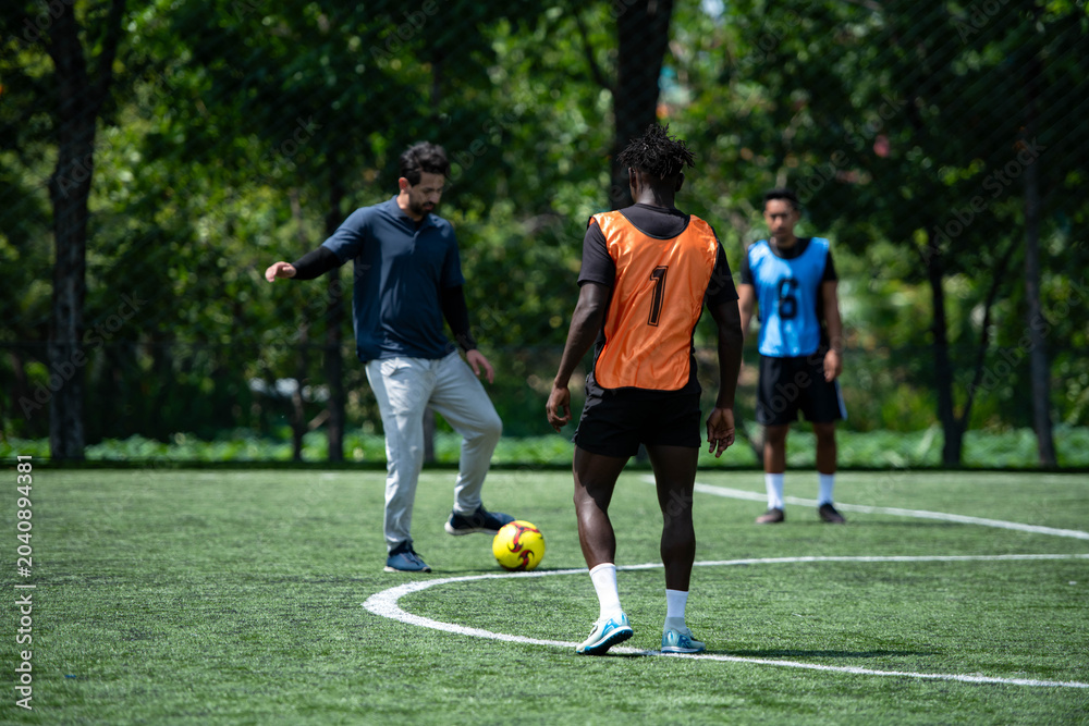 Obraz premium Soccer coach leading a practical training drill with players on an outdoor football field