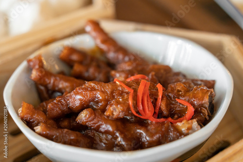 Fotografie Savory braised chicken feet with chilies in a bamboo steamer.