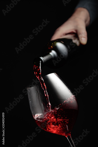 Pouring red wine in a glass goblet.