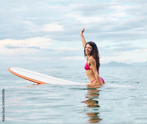Photography Portrait of a young woman surfing at the beach, holding surfboard, ocean waves,