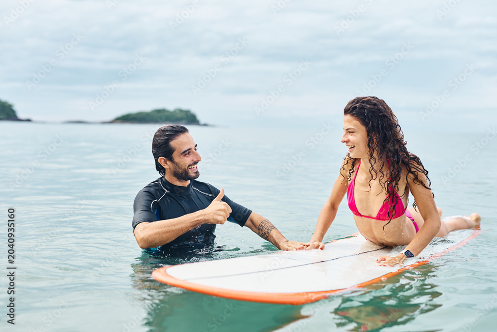 Obraz premium Portrait of a young couple surfing at the beach, holding surfboards, having fun together ocean waves, healthy life holidays adventure concept