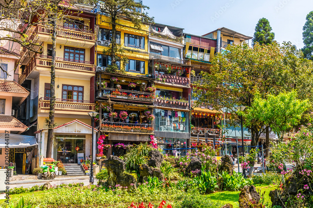 Fototapeta premium A view across a park towards flower decorated buildings in the centre of Sapa, Vietnam, in the morning