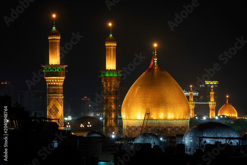 Karbala, Iraq - December 28, 2025: Golden dome and illuminated minarets of the Imam Hussain Shrine glowing at dusk in Karbala, Iraq