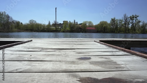 Two young women holding hands jumping from wooden pier into lake