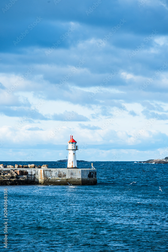 Obraz premium Lighthouse of norwegian town Vardo with blue sea and clouds in the background
