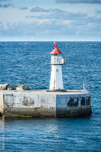 Lighthouse of norwegian town Vardo with blue sea and clouds in the background