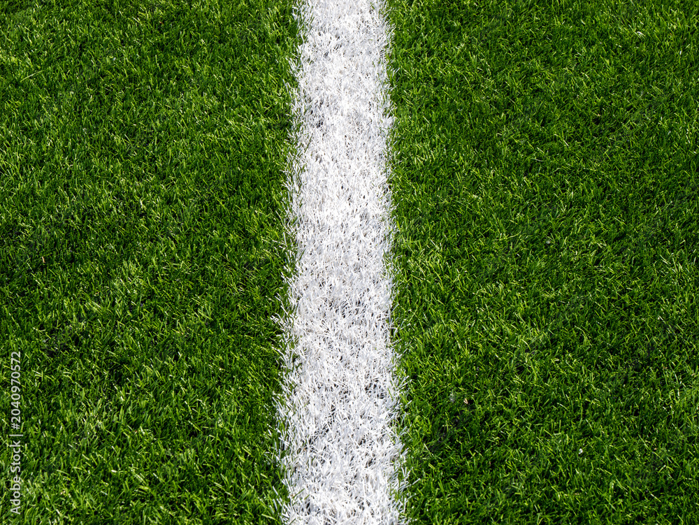 Fototapeta premium White painted line on green soccer turf closeup