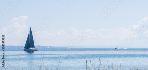 Foto Sailboat navigating calm waters on sunny lake constance