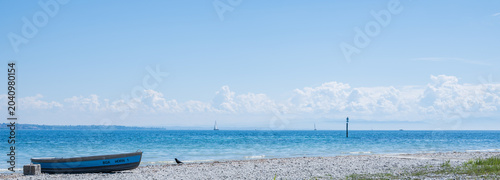Fotografi Blue rowboat resting on hörnle beach, lake constance