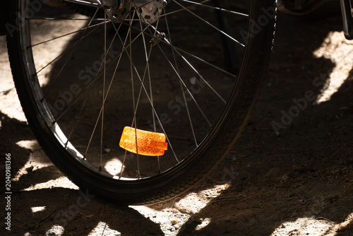Tableau sur toile Bicycle wheel with orange reflector in selective sunlight