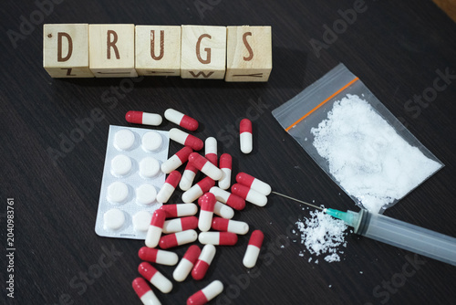 Tableau sur toile DRUGS, A syringe with pills, medication tablets, and a package of methamphetamine or heroin on a wooden table