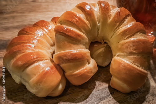 Fresh Golden Crescent Bread Rolls on Rustic Wooden Table.  Freshly baked golden crescent bread rolls with a glossy crust arranged on a rustic wooden tabletop. Warm natural tones, artisan bakery style.