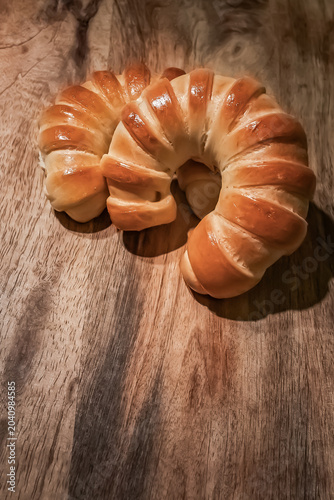 Fresh Golden Crescent Bread Rolls on Rustic Wooden Table.  Freshly baked golden crescent bread rolls with a glossy crust arranged on a rustic wooden tabletop. Warm natural tones, artisan bakery style.