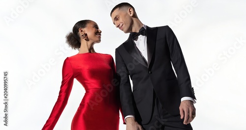 Elegant couple in formal attire posing against white background