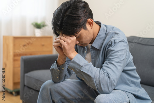 Obraz na plátne Stressed male feeling depressed and lonely on the sofa in the house