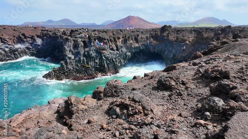 Powerful waves crash into a lava cove at Los Hervideros with black rocks and Atlantic Ocean on Lanzarote. Roaring waves inside a volcanic rock cove along the Atlantic