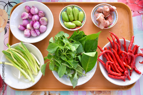 Foto Fresh Indonesian cooking ingredients including shallots, bilimbi, galangal, basil, bay leaves, green onions, and red curly chilies arranged in a colorful flat lay composition