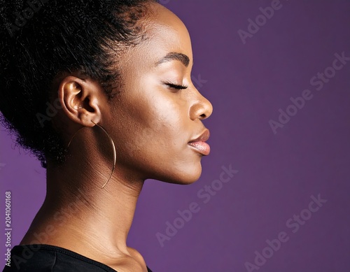 Serene Young Woman Posing in Side Profile Against Purple Studio Background
