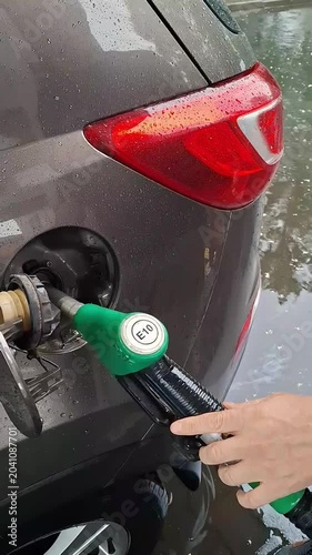 A close‑up video capturing the moment a fuel nozzle is inserted into a car’s tank during refueling. 