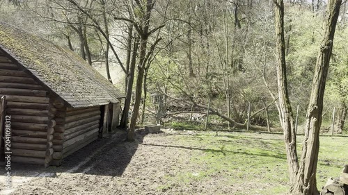 Old wooden log cabin surrounded by trees in a forest park during spring