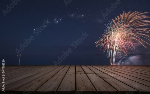 Fireworks display on a wooden dock at night with a starry sky