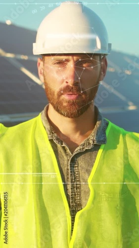 Male engineer professionally assessing solar panel setup with protective gear during golden hour sunlight