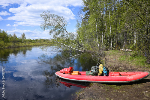 A red boat on a forest river.