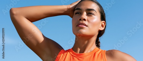 A confident athlete poses against a blue sky, showcasing strength and focus, ideal for fitness themes and motivational content aimed at aspiring athletes.
