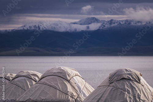 Photos Yurt Rooftops Against Snow-Capped Mountains and Lake in Kyrgyzstan