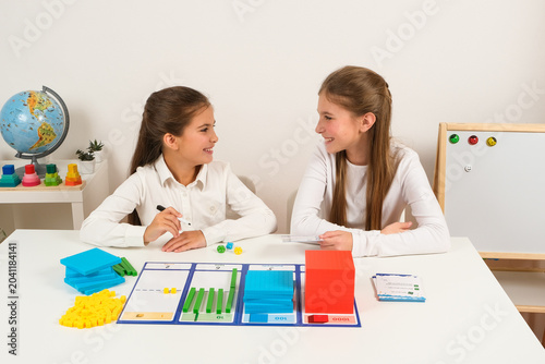 Fotografía Two young students sitting at a desk, smiling and collaborating on a math lesson using colorful base ten blocks to understand place values from ones to thousands